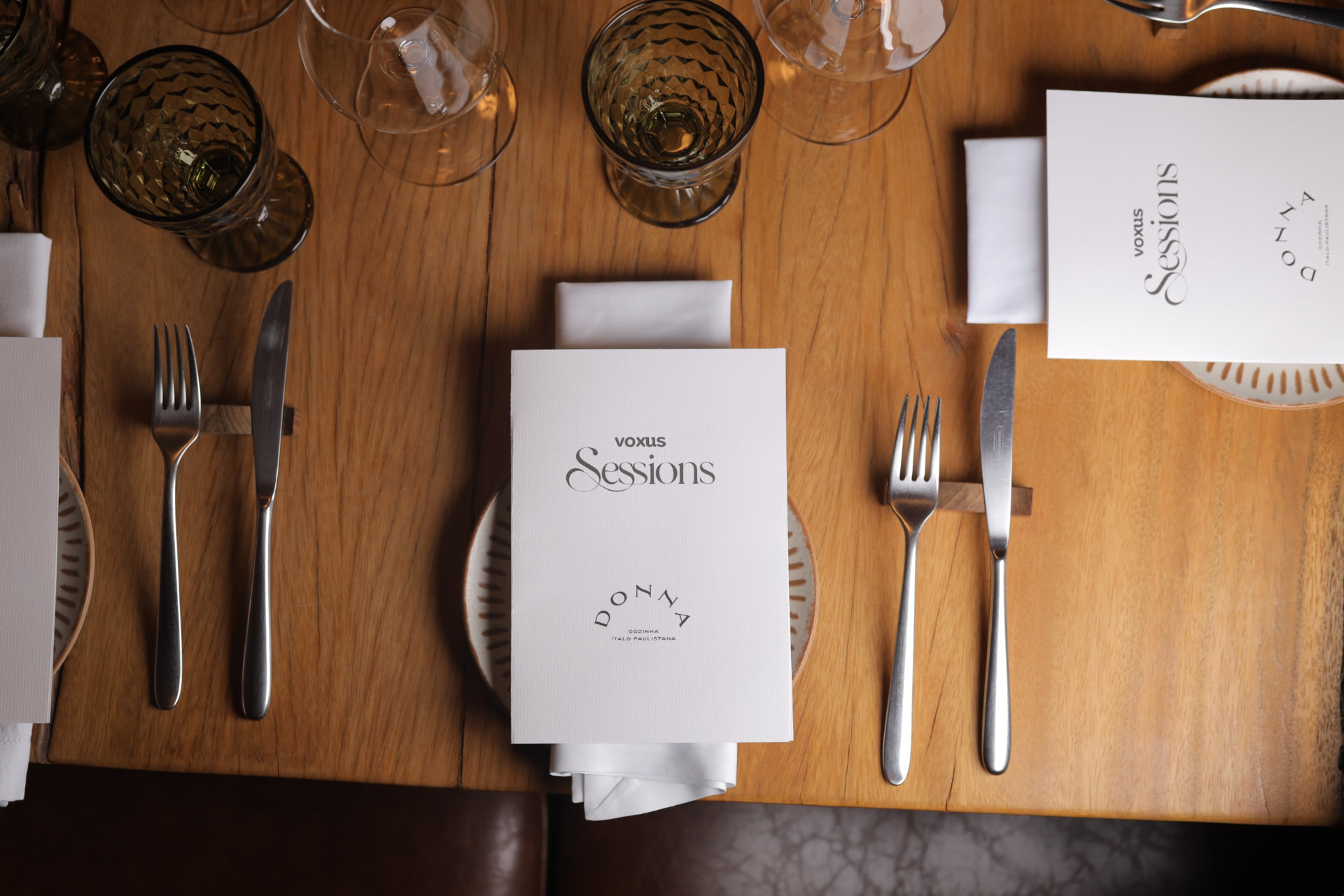 Mesa vista de cima, com menus impressos, taças e talheres