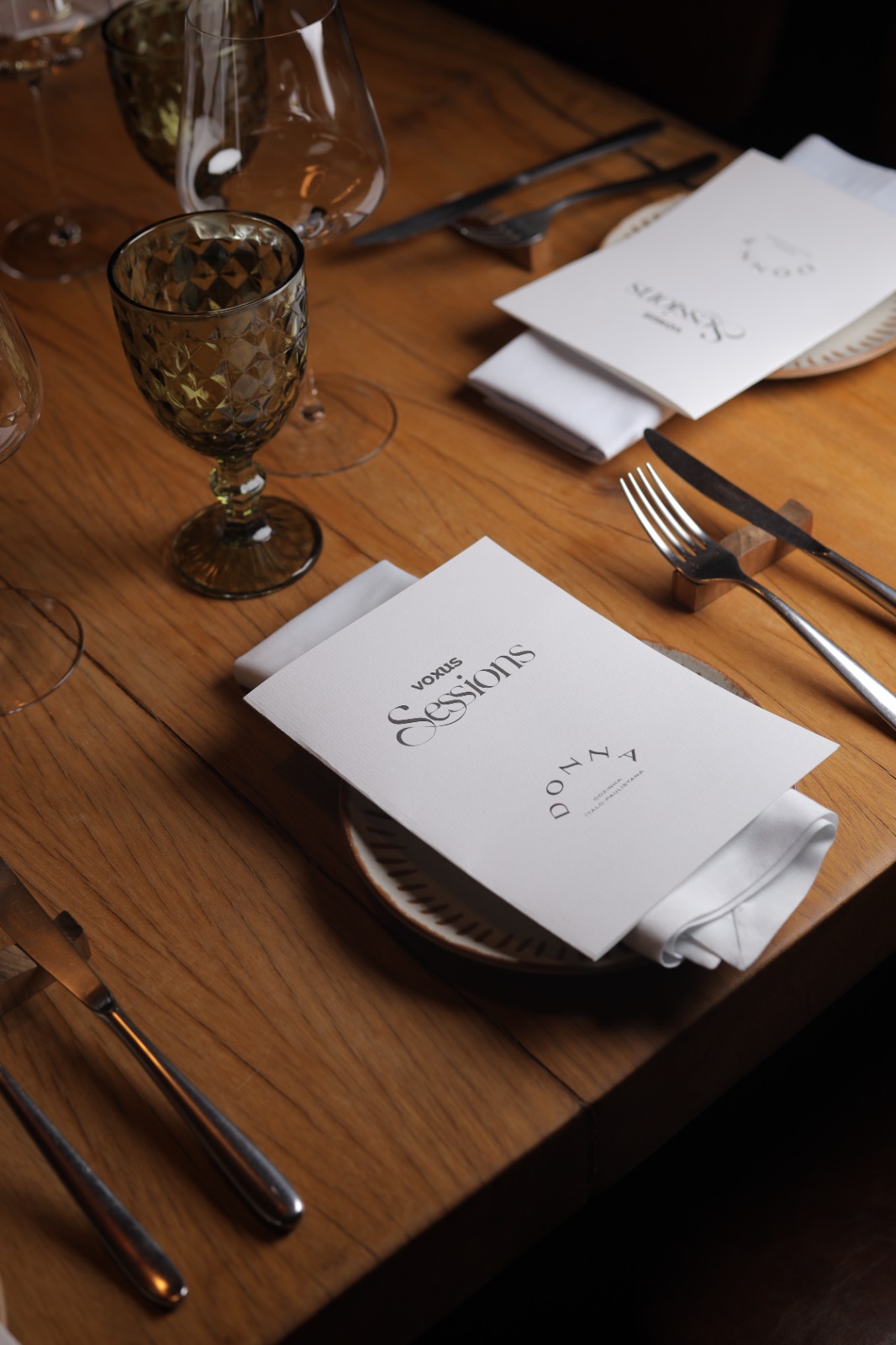 Mesa posta para um jantar reservado, com menu impresso e taças